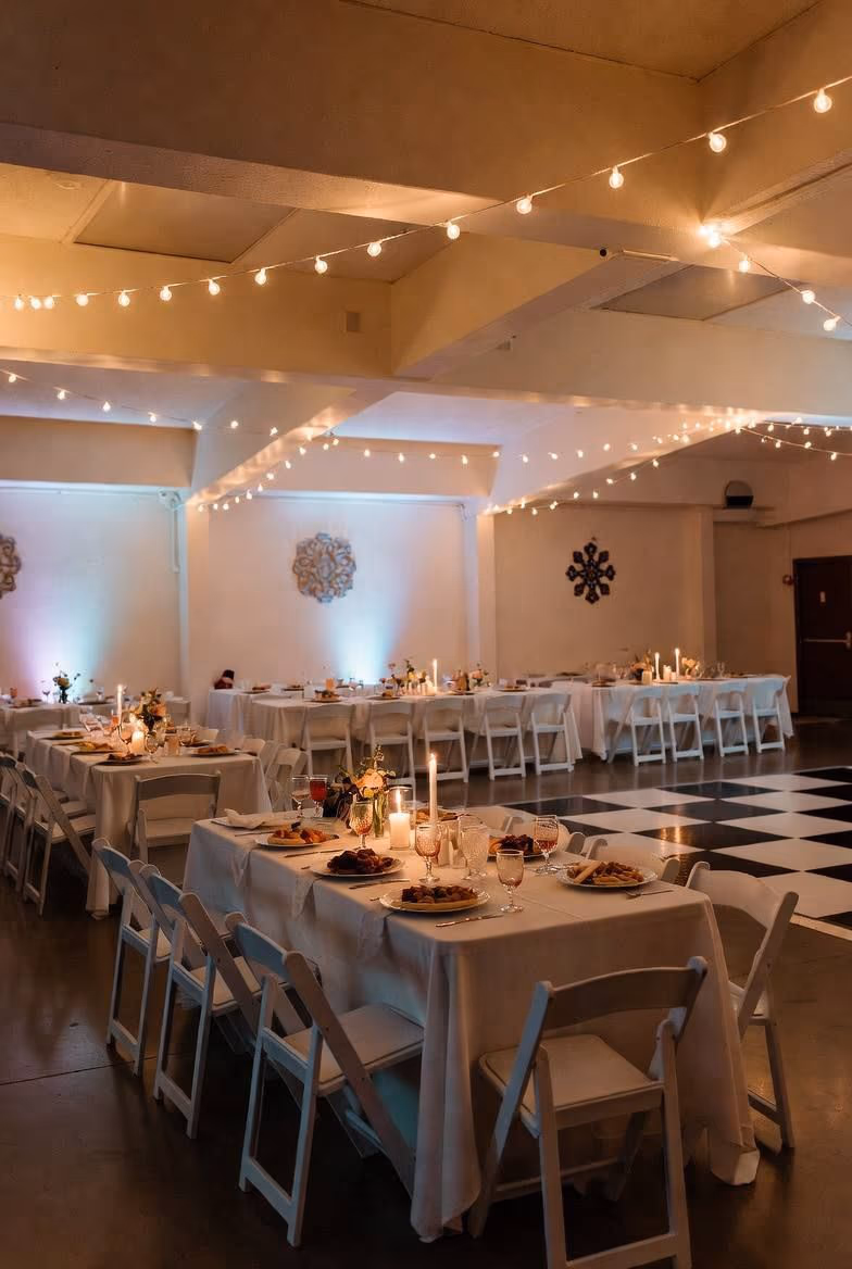 Indoor reception hall with string lights and decorated tables